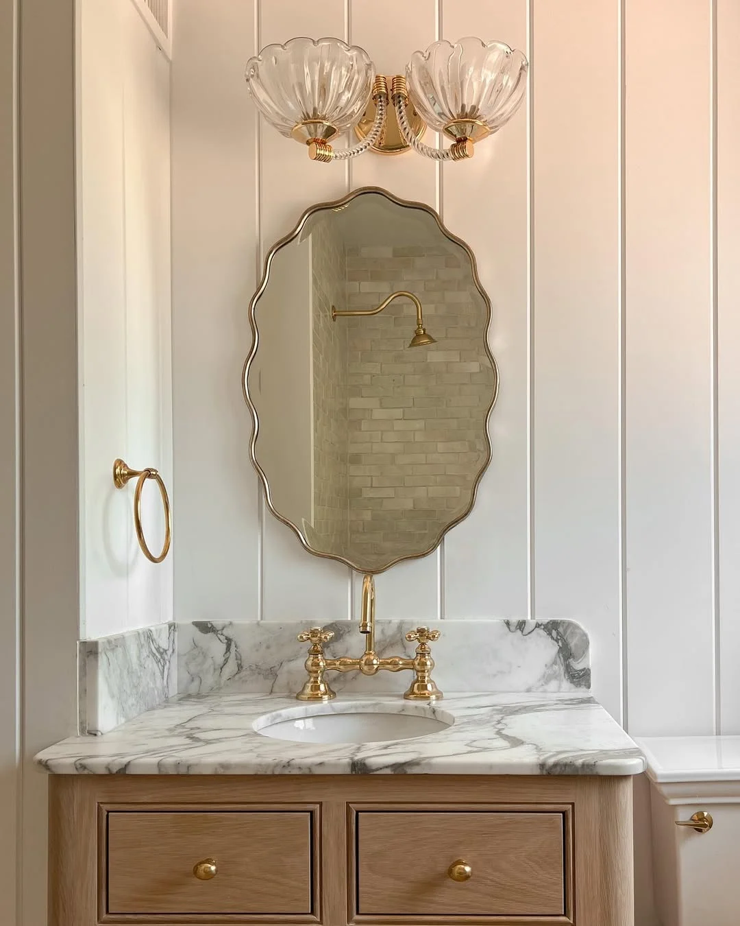 Elegant Bathroom with Scalloped Mirror and Glass Sconce